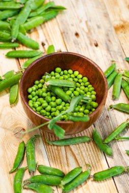 kahverengi çanak içinde closeup yeşil bezelye, ahşap masa üzerinde.