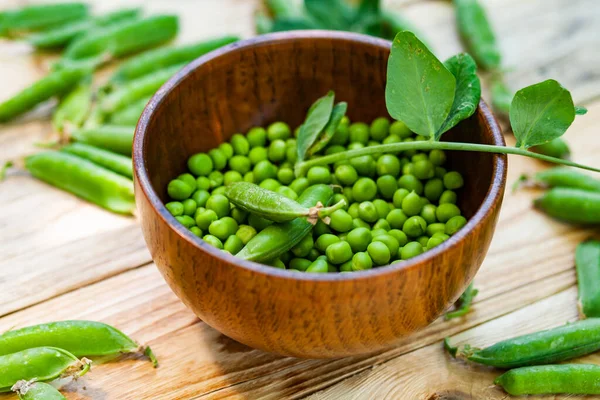 Primer Plano Guisantes Verdes Plato Marrón Sobre Mesa Madera —  Fotos de Stock