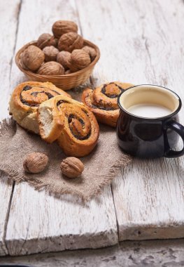 Reçelli ev yapımı çörekler, cevizli ve sütlü eski ahşap masada servis ediliyor.