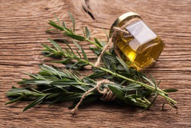 Ahşap kırsal arka planda biberiye dalı olan önemli biberiye yağından yapılmış şişe camı..