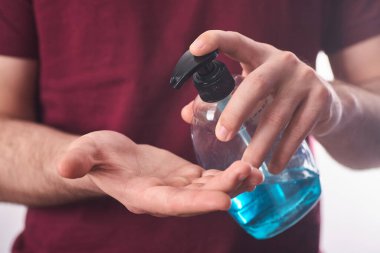 Yakından çekilen adamlar COVID-19 'a karşı antibakteriyel sıvı sabun kullanıyor. Adam mavinin üzerine jel sürüyor. Antiseptik, boş..