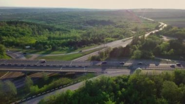 Akşam trafiği üzerinde uçan bir insansız hava aracı. Otoyol ve kamyonlar, kavşak, iki katlı yol ayrımı. Çevre yolu, hat.