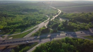 Akşam trafiği üzerinde uçan bir insansız hava aracı. Otoyol ve kamyonlar, kavşak, iki katlı yol ayrımı. Çevre yolu, hat.
