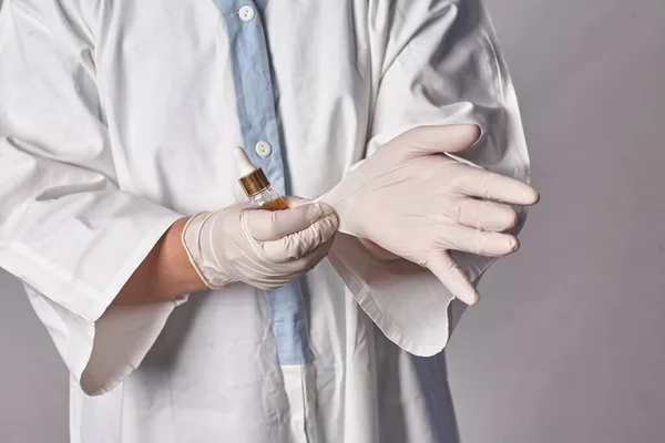 保护医护人员免受感染 一位女医生戴上医疗手套 背景是白色的 面带微笑 病人检查前的个人防护设备 — 图库照片