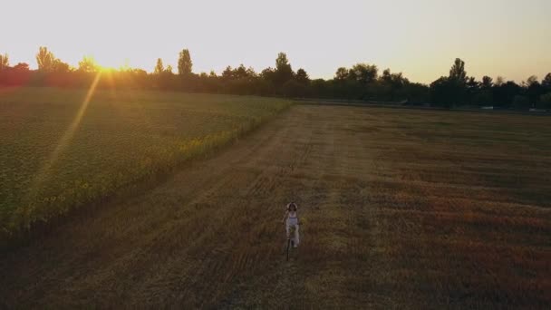 Draufsicht einer Frau im weißen Kleid, die ein Fahrrad auf einem Feld mit Sonnenblumen führt. Drohnen-Zukunft 4K. — Stockvideo