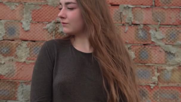 ईंट की दीवार के सामने युवा मुस्कुराते हुए महिला का चित्र बंद करें — स्टॉक वीडियो