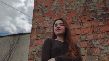 Tuğla duvarın önünde gülümseyen genç kadının portresini kapat.