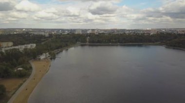 Sonbahar ağaçlarıyla dolu bir parktaki göl manzarası. Kishinev, Moldova. Suyun üzerinde destansı bir uçuş. Gündüz vakti renkli sonbahar ağaçları. Drone sarı ağaçlı bir göl boyunca uçar. 4K İHA Atışı.