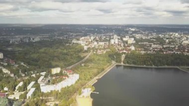 Sonbahar ağaçlarıyla dolu bir parktaki göl manzarası. Kishinev, Moldova. Suyun üzerinde destansı bir uçuş. Gündüz vakti renkli sonbahar ağaçları. Drone sarı ağaçlı bir göl boyunca uçar. 4K İHA Atışı.