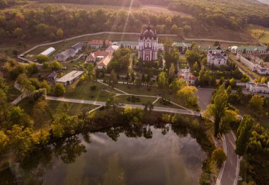 Etrafı sonbahar ormanlarıyla çevrili bir Hıristiyan manastırı üzerinde uçmak. Kurky Manastırı, Moldova Cumhuriyeti.