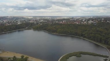 Sonbahar ağaçlarıyla dolu bir parktaki göl manzarası. Kishinev, Moldova. Suyun üzerinde destansı bir uçuş. Gündüz vakti renkli sonbahar ağaçları. Drone sarı ağaçlı bir göl boyunca uçar. 4K İHA Atışı.