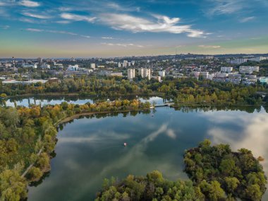 Sonbahar ağaçlarıyla dolu bir parktaki göl manzarası. Kishinev, Moldova. Suyun üzerinde destansı bir uçuş. Gündüzleri renkli sonbahar ağaçları.