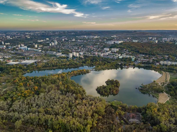 Sonbahar ağaçlarıyla dolu bir parktaki göl manzarası. Kishinev, Moldova. Suyun üzerinde destansı bir uçuş. Gündüzleri renkli sonbahar ağaçları.