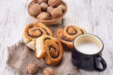 Reçelli ev yapımı çörekler, cevizli ve sütlü eski ahşap masada servis ediliyor.