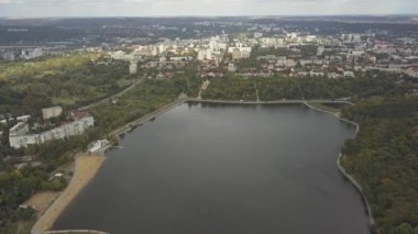 Sonbahar ağaçlarıyla dolu bir parktaki göl manzarası. Kishinev, Moldova. Suyun üzerinde destansı bir uçuş. Gündüz vakti renkli sonbahar ağaçları. Drone sarı ağaçlı bir göl boyunca uçar. 4K İHA Atışı.