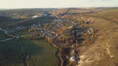 Güneşli bir yaz gününde banliyöde hava aracı uçuşu. Çatı ve bahçe havuzları parlak ve renkli görünüyor. Ağaçlar ve çimenler yemyeşil.