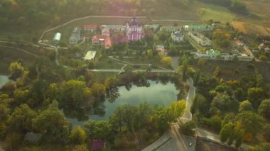 Günbatımında sonbahar ormanlarıyla çevrili bir Hıristiyan manastırının üzerinden uçmak. Kurky Manastırı, Moldova Cumhuriyeti.