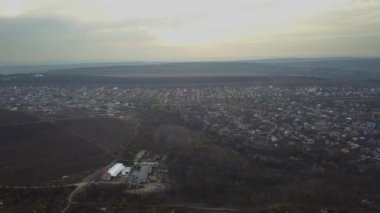 Güneşli bir yaz gününde banliyöde hava aracı uçuşu. Çatı ve bahçe havuzları parlak ve renkli görünüyor. Ağaçlar ve çimenler yemyeşil.
