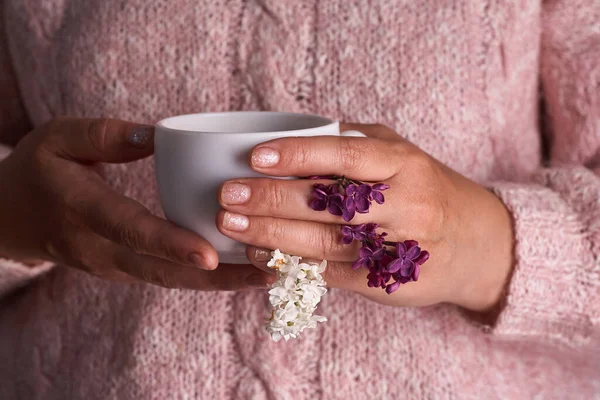 コーヒーの白いカップを持っている女性の手 美しいライラックの花と 飲み物ファッション朝 — ストック写真