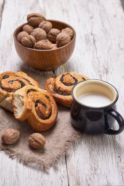 Reçelli ev yapımı çörekler, cevizli ve sütlü eski ahşap masada servis ediliyor.