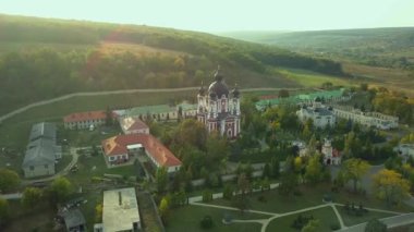 Günbatımında sonbahar ormanlarıyla çevrili bir Hıristiyan manastırının üzerinden uçmak. Kurky Manastırı, Moldova Cumhuriyeti.