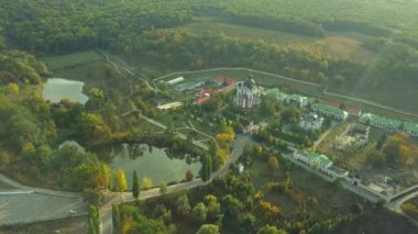 Günbatımında sonbahar ormanlarıyla çevrili bir Hıristiyan manastırının üzerinden uçmak. Kurky Manastırı, Moldova Cumhuriyeti.