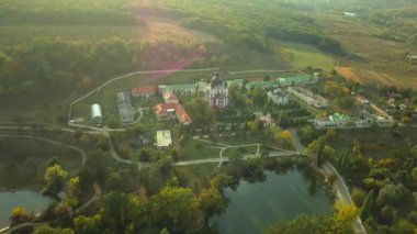 Günbatımında sonbahar ormanlarıyla çevrili bir Hıristiyan manastırının üzerinden uçmak. Kurky Manastırı, Moldova Cumhuriyeti.