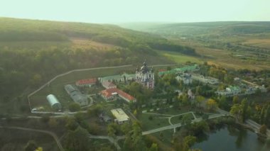 Günbatımında sonbahar ormanlarıyla çevrili bir Hıristiyan manastırının üzerinden uçmak. Kurky Manastırı, Moldova Cumhuriyeti.