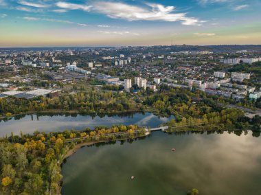 Sonbahar ağaçlarıyla dolu bir parktaki göl manzarası. Kishinev, Moldova. Suyun üzerinde destansı bir uçuş. Gündüzleri renkli sonbahar ağaçları.