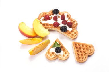 Beyaz arka planda yalıtılmış böğürtlen ve şeftalili waffle.
