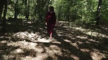 Kafkasyalı esmer kadın sonbahar ağaçlarının arasında yürüyor. Çemberin arkasından takip ediyor. Hikaye anlatıyorum. Gerçek yetişkin insanlar yaz ormanlarında yalnız..