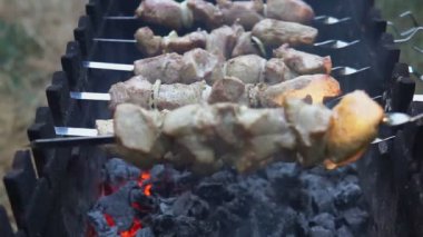 Bir adamın elleri şişleri döndürüyor. Şiş kebap. Kömür ızgarasında kızartılan domuz eti mi kuzu eti mi? Kalanı da ızgara et..