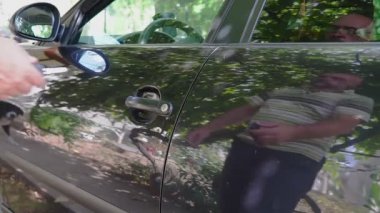 Bir adamın eli arabanın kapısını anahtarla açar.