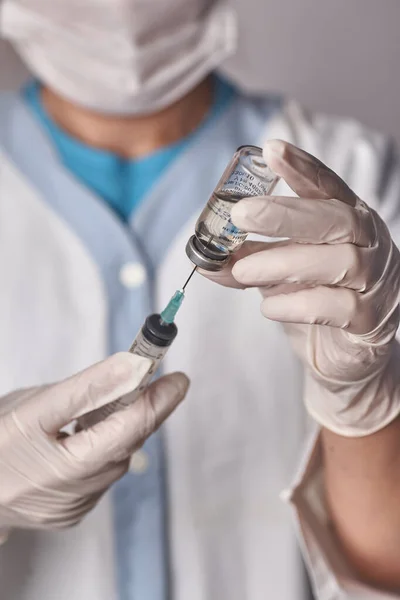 Läkaren får in vaccinet i sprutan. Glasflaska i teknikers hand. En flaska med ett botemedel håller en hand i silikonhandskar. Ett genombrott i behandlingen. Vaccinmedicinska undersökningar. Pandemi. — Stockfoto