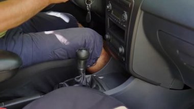 Gün batımında araba sürerken vites değiştiren bir kadın eli.