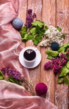 Kahve fincanı ve bahçe masasında renkli leylak çiçekleri.