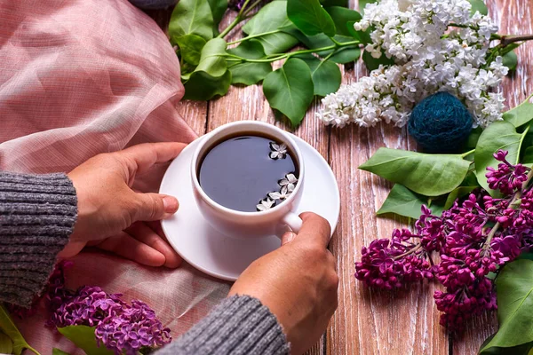 上から見ると 春のライラックの花の枝が木の背景に咲く朝のコーヒーカップを手に持っています フラット地下スタイルを置く 高価な色だ 花の創造的なデザイン — ストック写真