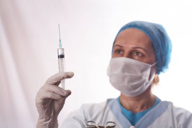Kadın doktor, hastaya iğne yapmak için şırıngayı hazırlıyor..