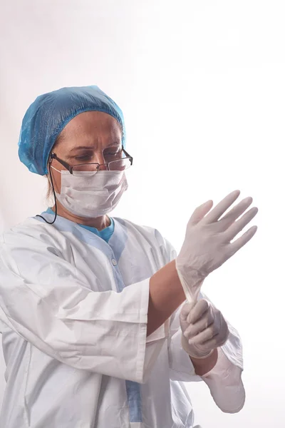 保护医护人员免受感染 一位女医生戴上医疗手套 背景是白色的 面带微笑 病人检查前的个人防护设备 — 图库照片