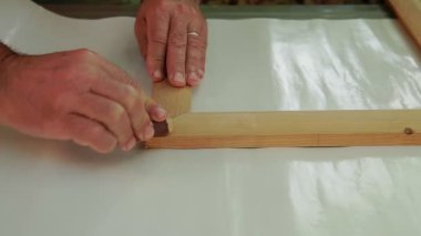 Marangoz elle ahşap bir çerçeve öğütür.