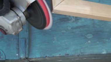 Bir adam ahşap bir tahtayı çok tozlu öğütücüyle tutar ve öğütür.