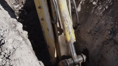 Büyük metal kazıcı, kırsal bölgelerdeki yol çalışmaları sırasında çukur kazarken toprak topluyor. Karındeşen kovası güneşli bir günde bir inşaat alanında toprak ve taş kazıyor..