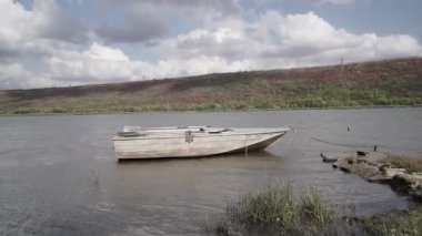 Eski metal balıkçı teknesi nehrin sığ sularında demirlemiş.