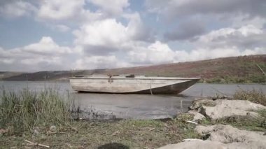 Eski metal balıkçı teknesi nehrin sığ sularında demirlemiş.