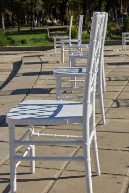 Sosyal uzaklık için hazırlanmış geniş bir grup boş beyaz sandalye açık hava iş konferansına konuk ağırlamaya hazır. COVID-19 salgın sırasında sağlık ve güvenlik tedbirleri insanlar arasında mesafe gerektirir