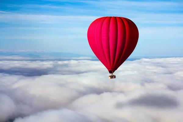 A lonely red hot air balloon floats above the clouds. Concept leader, success, loneliness, victory