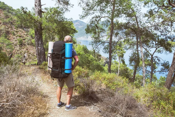 An elderly tourist with a backpack on the hiking trail