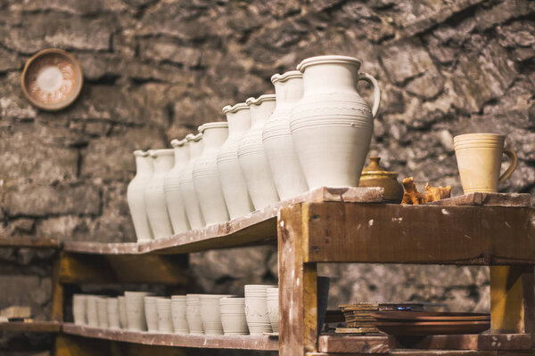 Кувшины из необработанной глины на полке в мастерской
