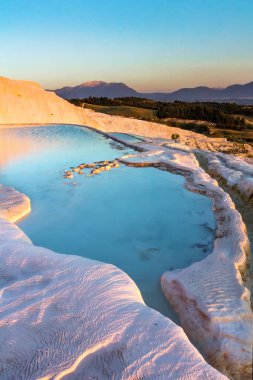 Pools of Pamukkale in Turkey in sunset, contains hot springs and travertines, terraces of carbonate minerals left by the flowing water, UNESCO World Heritage Site clipart