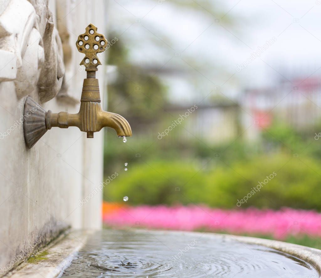 Water pouring from a tap in an old fountain